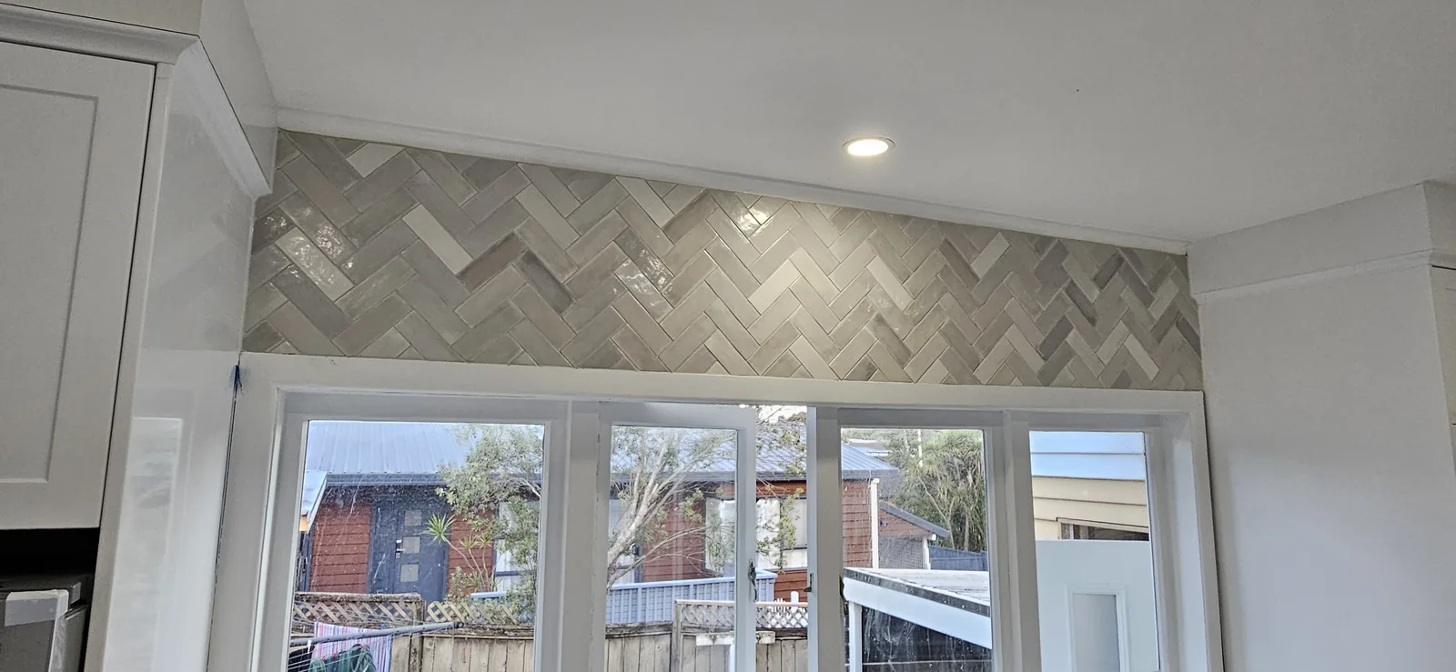 Tiled kitchen splashback with precise cuts around the benchtop in an Auckland kitchen by Tarara Tiling