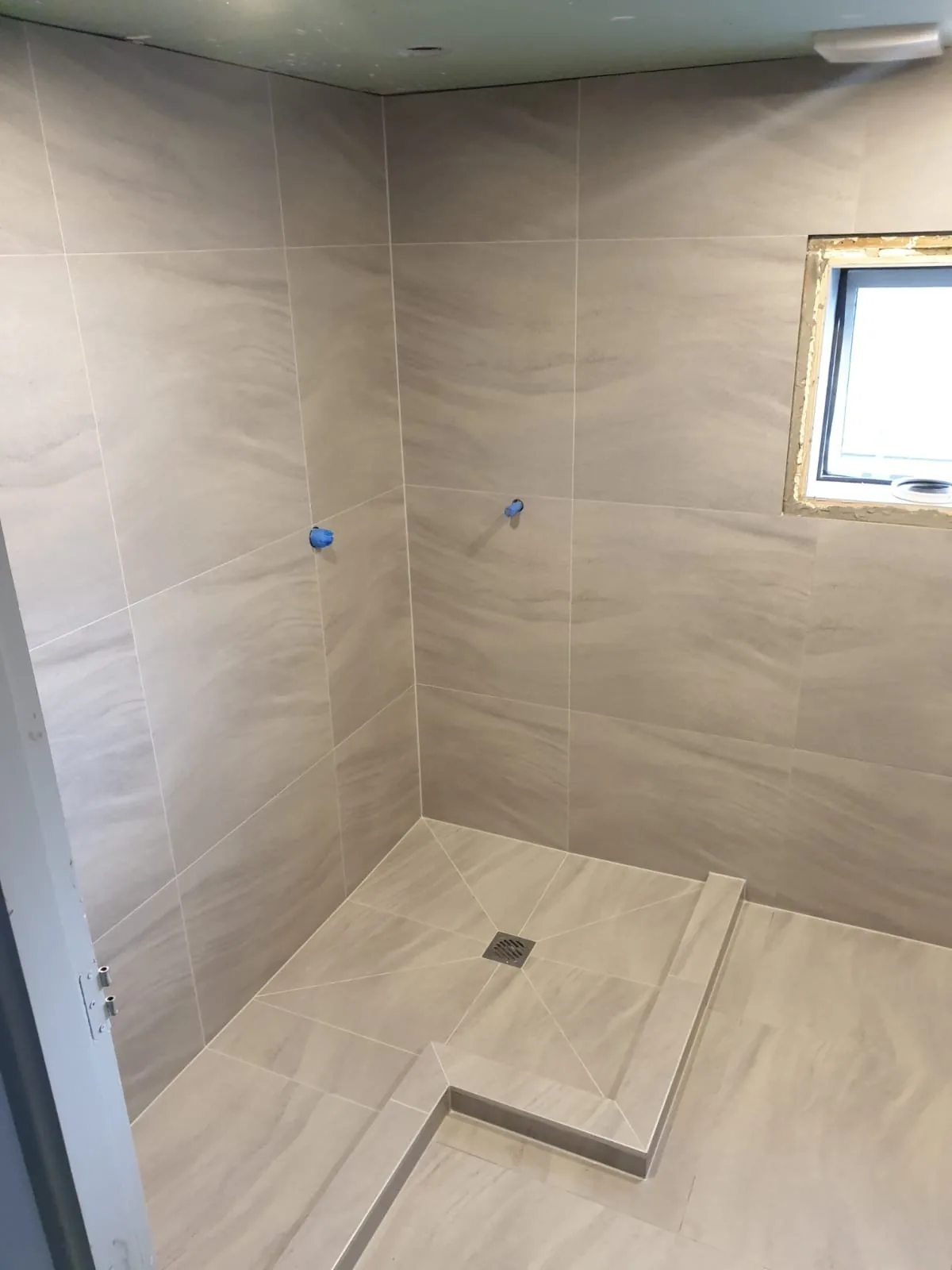 Fully tiled walk-in shower with large-format tiles in an Auckland bathroom by Tarara Tiling